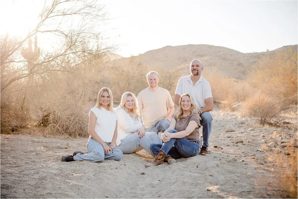 Adult family laughing together in the sand at sunset