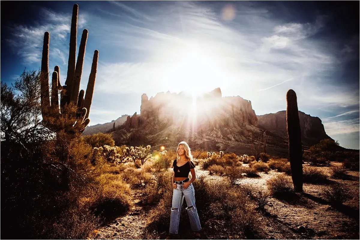 Senior standing below desert buttes with a sunburst