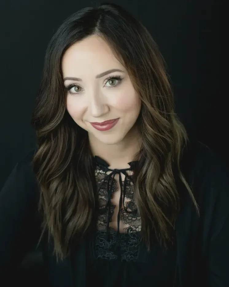 Striking studio headshot of a woman with long dark hair on a dark backdrop